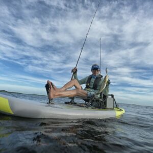 Foto di un pescatore mentre sta tirando su un pesce sul suo Kayak Gonfiabile da Pesca